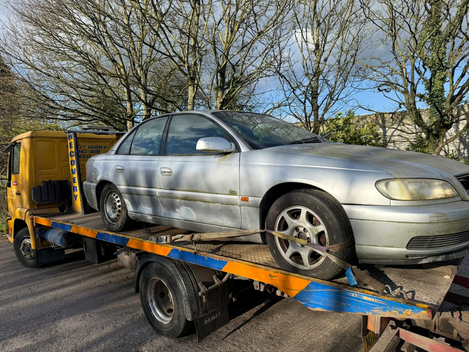 Scrap car loaded on yellow recovery truck